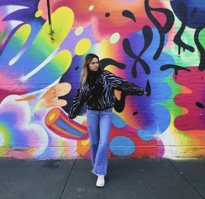 Cliente posant devant une fresque murale colorée